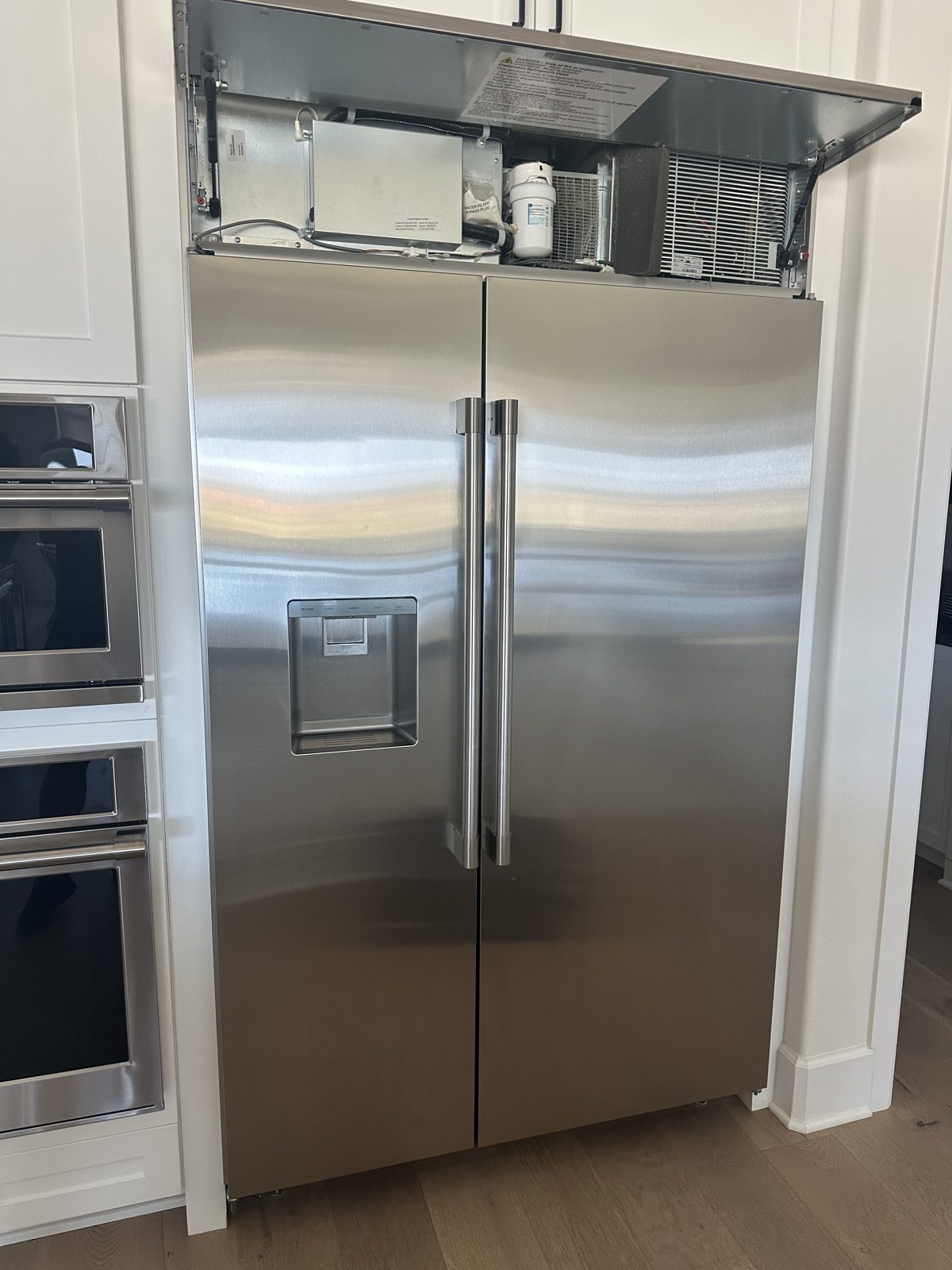 Monogram 48-inch built-in side-by-side refrigerator with the top machine compartment open for service