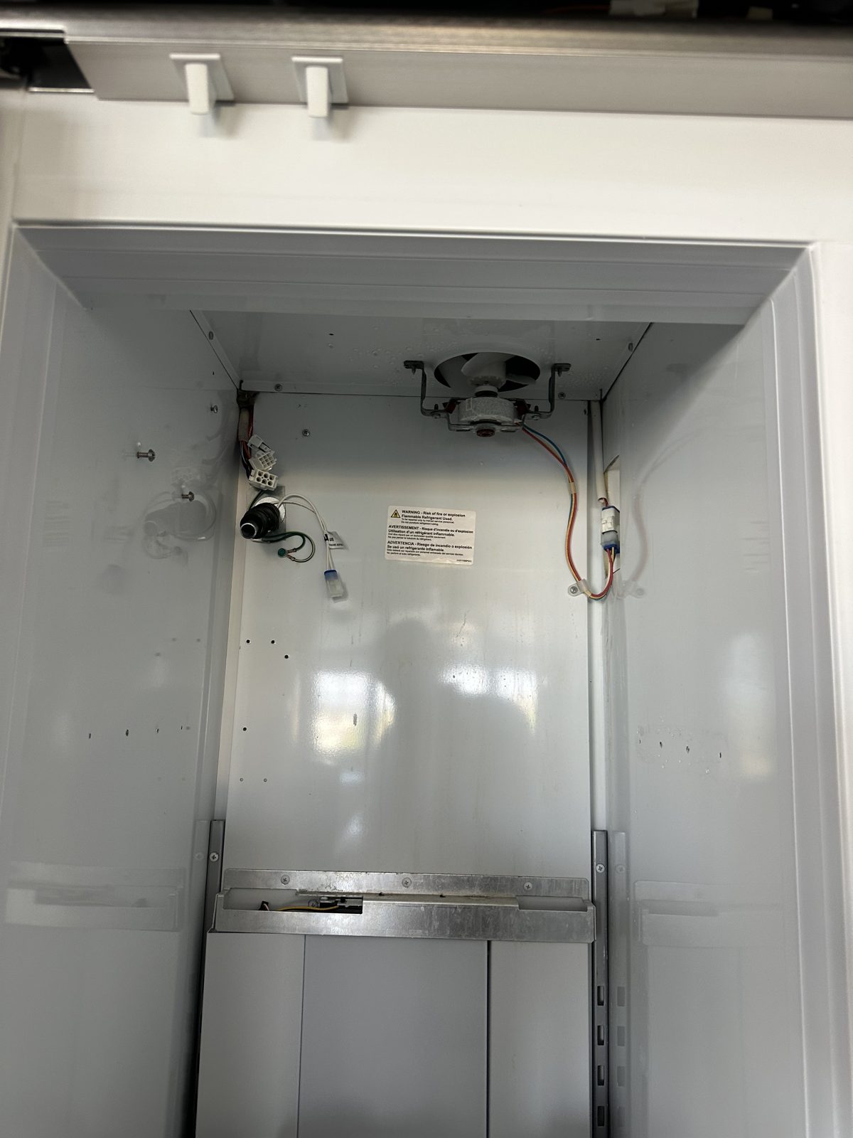 Monogram freezer section with the rear panel removed, showing the evaporator fan and wiring