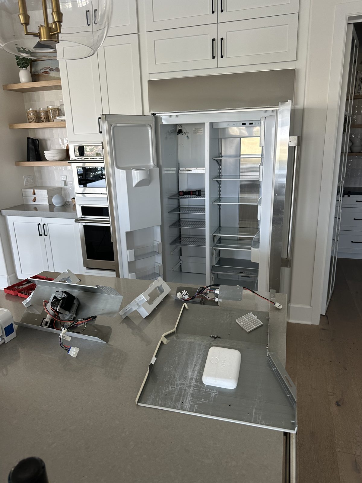 Monogram freezer components removed during repair, including the fan assembly and rear panel