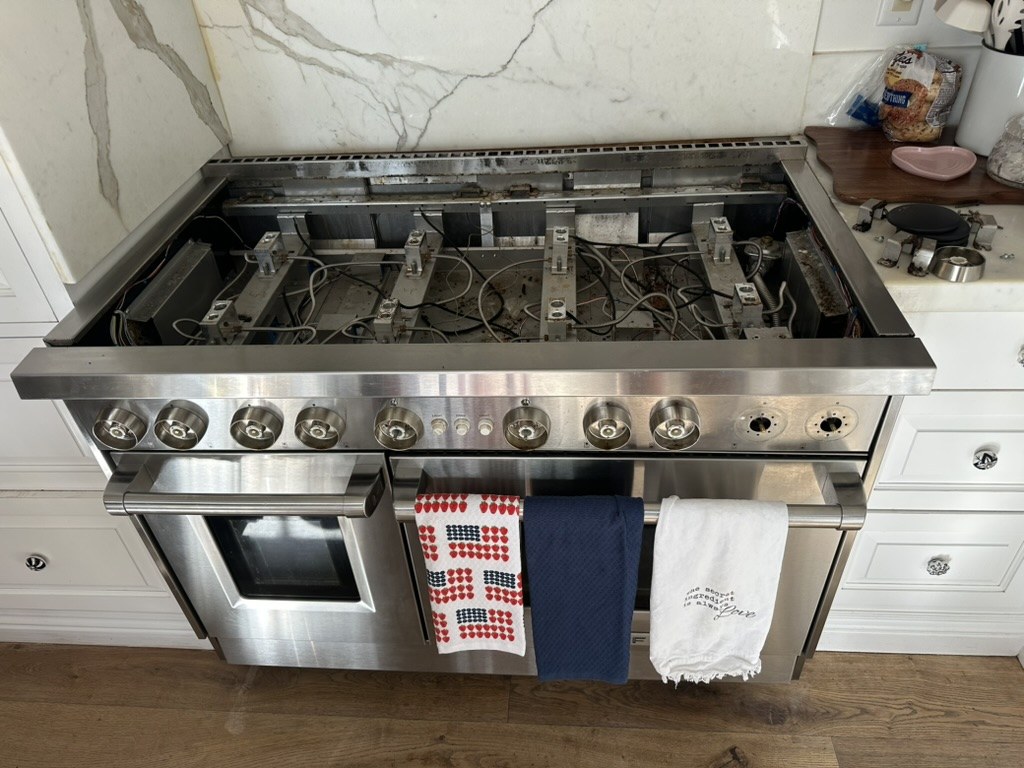 Wolf rangetop with burner grates and cooktop removed, exposing the spark modules and igniter wiring