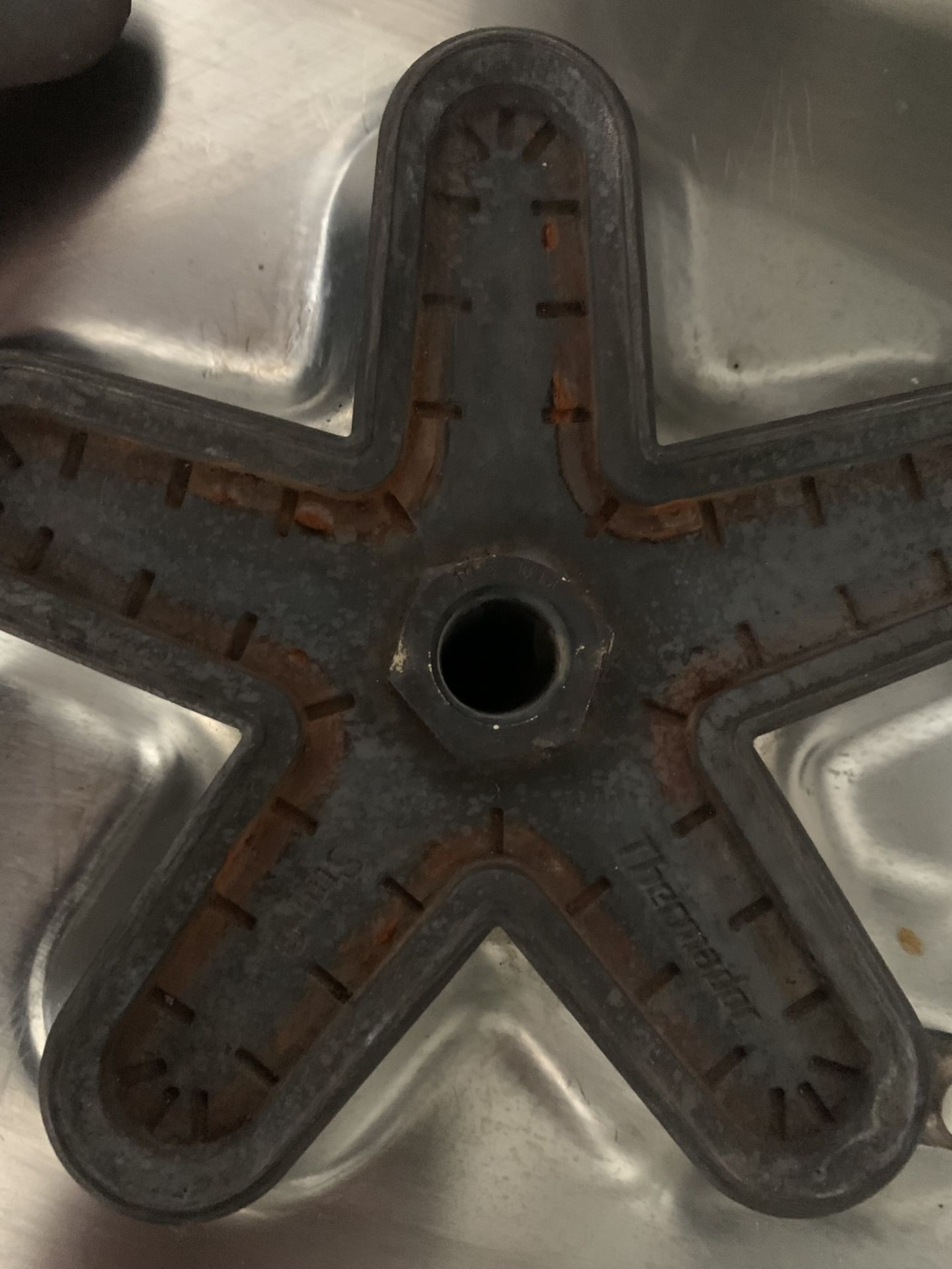 Star-burner cap removed for cleaning during rangetop maintenance